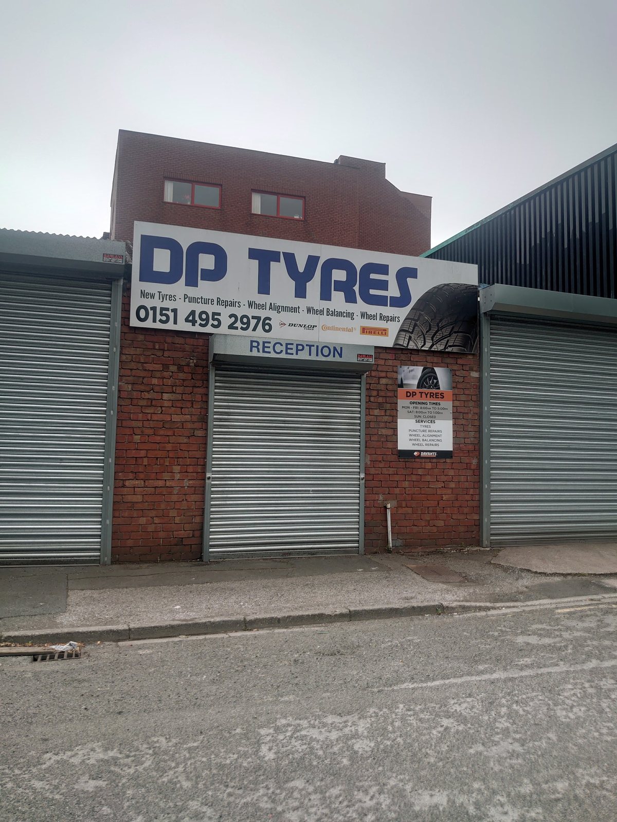 The DP TYRES sign above the reception shutter, with the opening times and services board