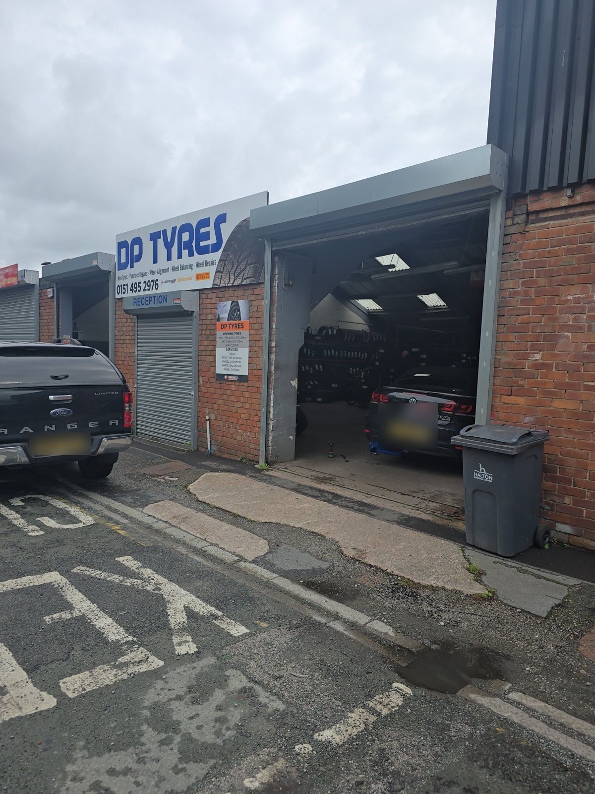 The open bay at D P Tyres with a car inside and tyre racks behind