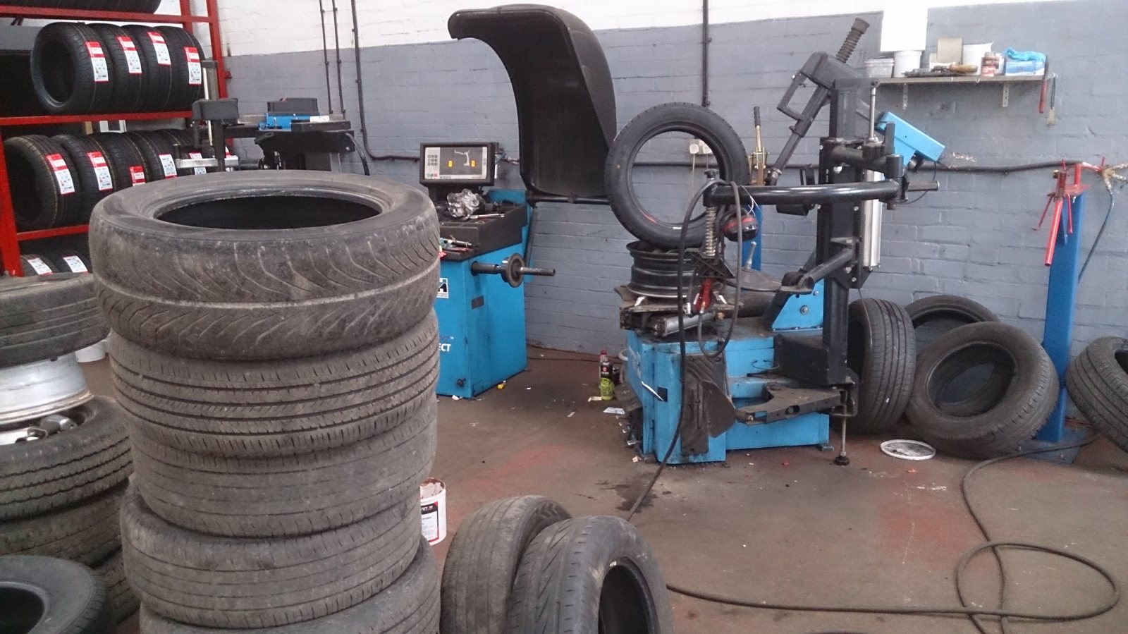 Tyre changer and wheel balancer in the D P Tyres workshop, with stacks of tyres